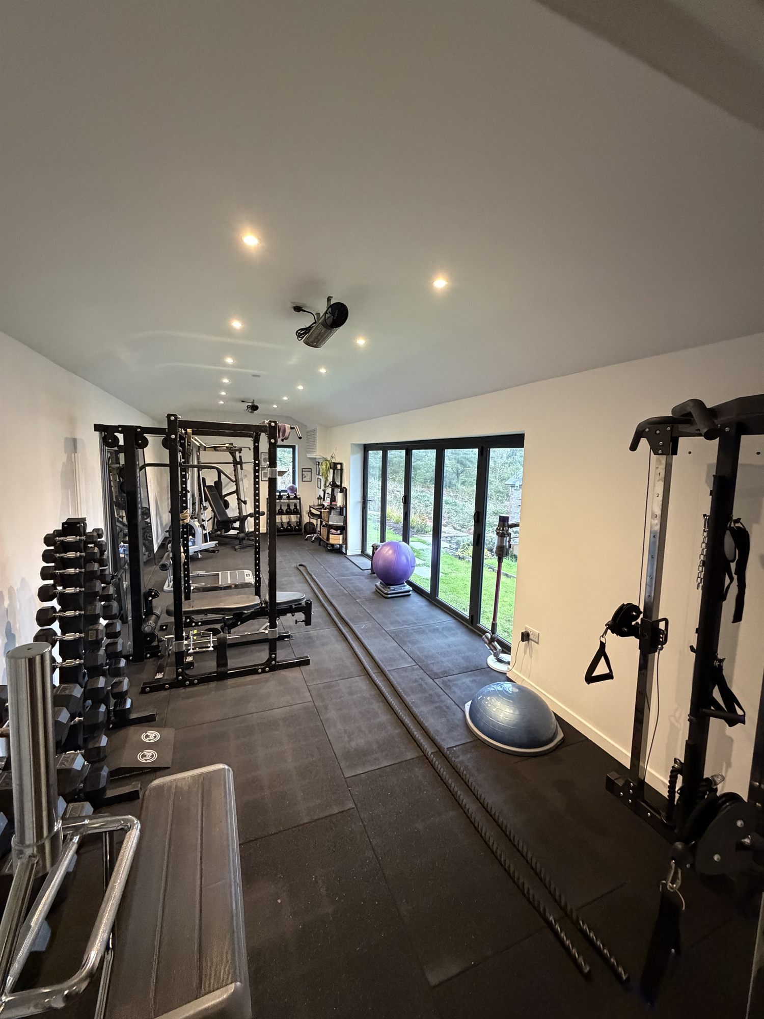 The Battle Bodies private gym, with power racks, dumbbells and bifold doors onto the garden